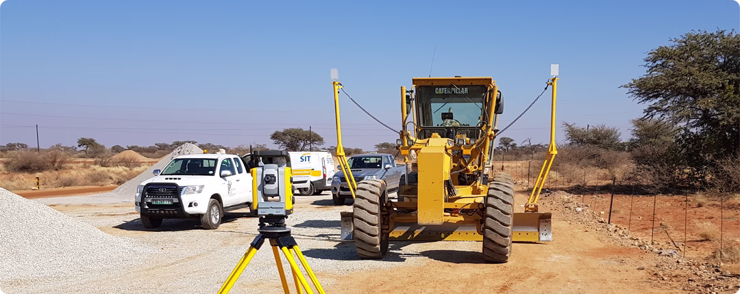 Motor grader on a road construction site using Trimble Earthworks technology for precise grading and excavation.