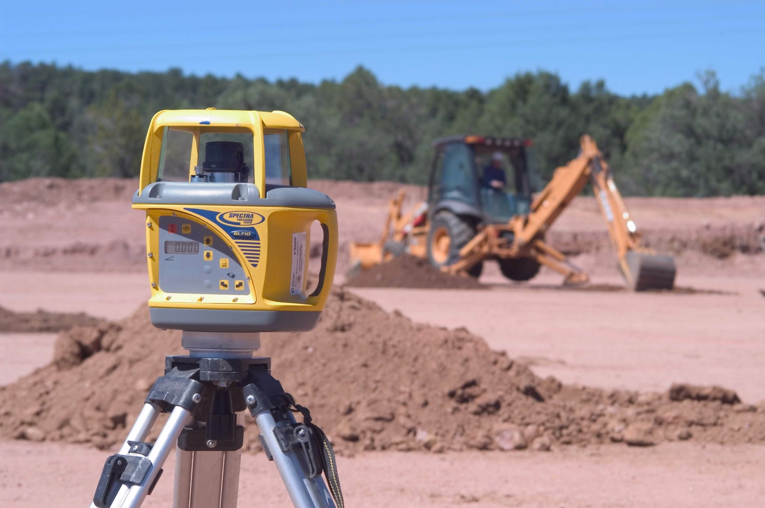 Laser level and excavator showing construction workflows automation in earthmoving